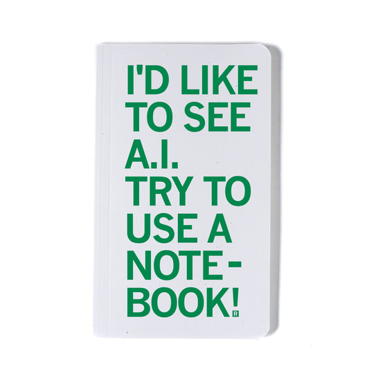 White notebook made in the USA with green text that reads, Id like to see A.I. try to use a notebook!.