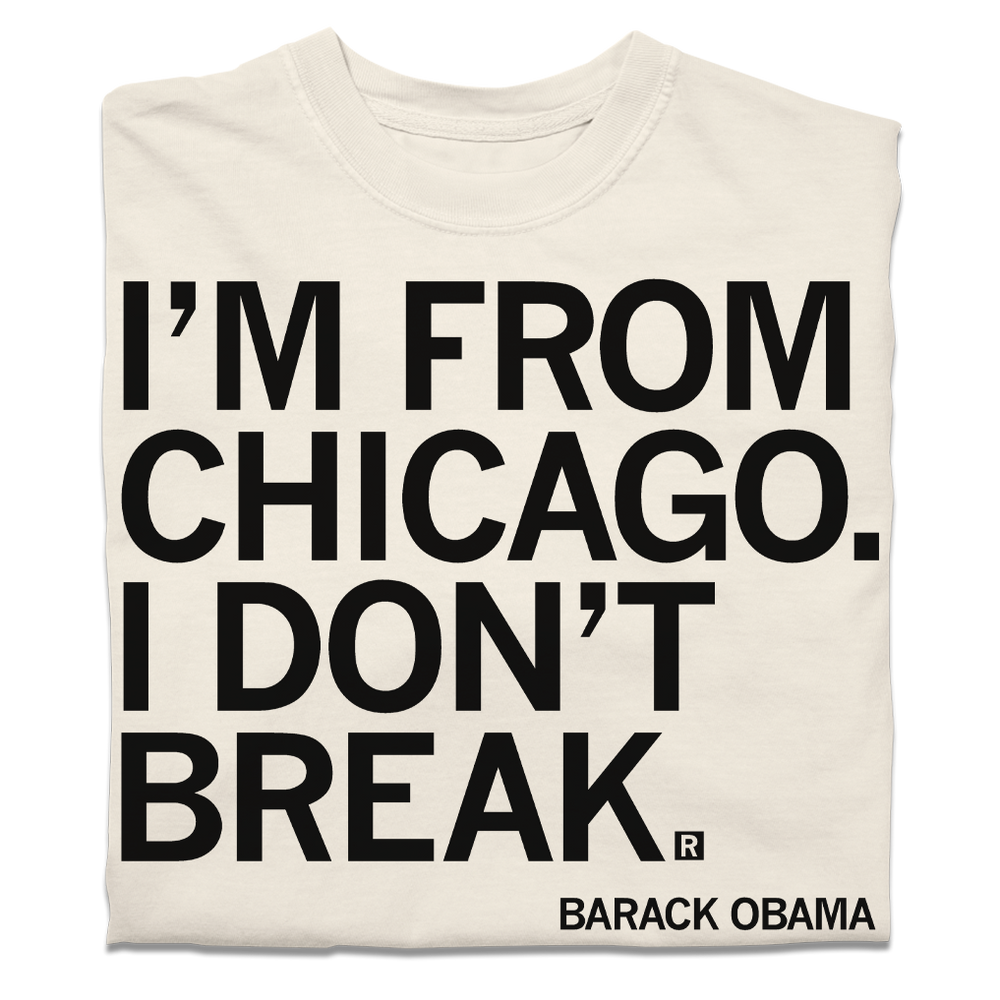 A folded off-white t-shirt with black ink text that says, ""I'm from Chicago. I don't break." - Barack Obama."