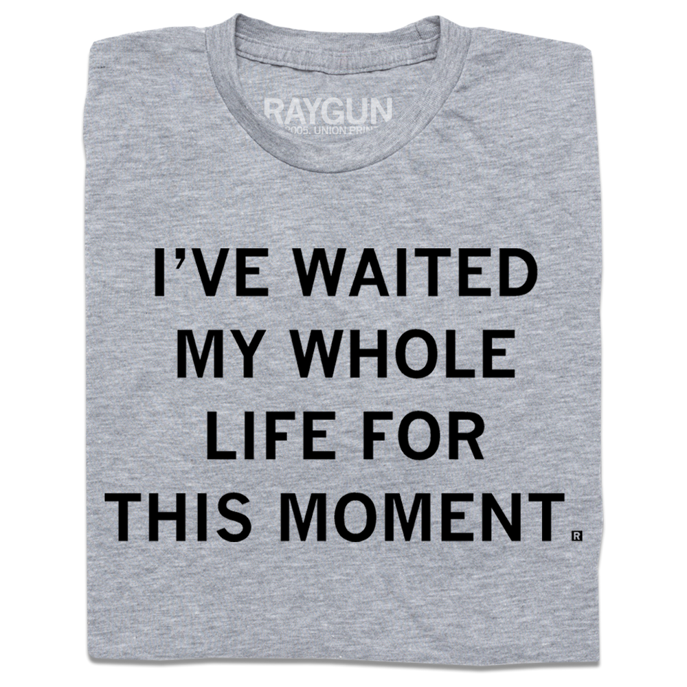 A folded heather grey t-shirt with centered black ink text that reads "I've waited my whole life for this moment."