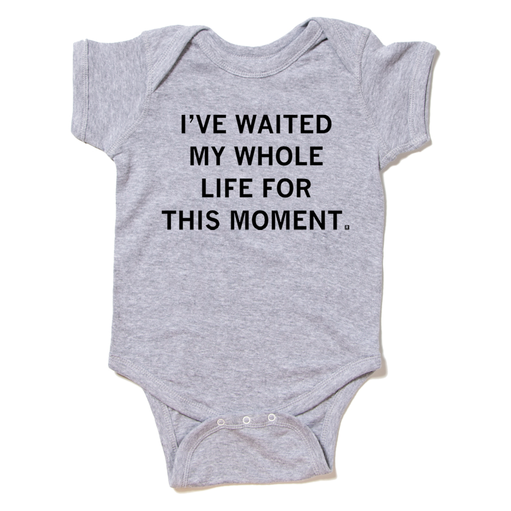 A heather grey baby onesie with centered black ink text that reads "I've waited my whole life for this moment."