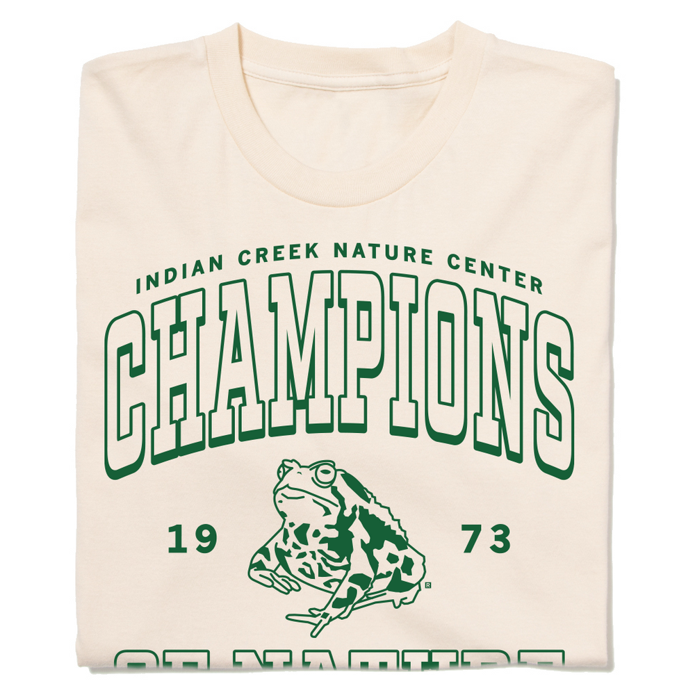 An off white t-shirt with kelly green ink that says, "Indian Creek Nature Center: Champions of Nature since 1973. Cedar Rapids, Iowa" with an illustration of a toad in the center.