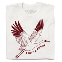 A folded off white t-shirt with maroon ink depicting a Whooping Crane in flight with the text "I Give a Whoop" underneath it.