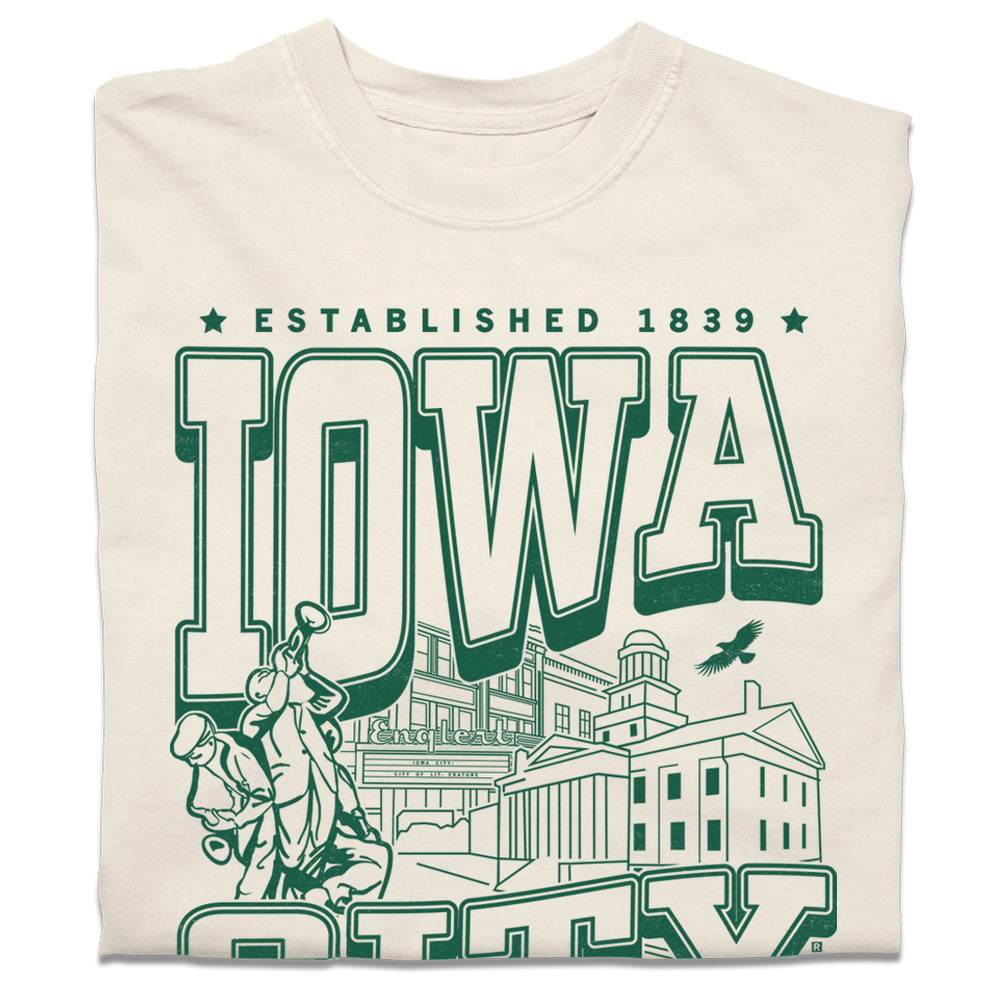 A folded heavyweight cream t-shirt with kelly green ink that says, "Iowa City: Established 1839. Iowa's first state Capital" with and illustrated Iowa City staples in the center, including the Englert Theater and the old Capitol Building.