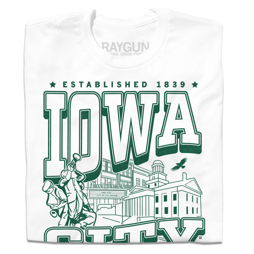 A folded white t-shirt with kelly green ink that says, "Iowa City: Established 1839. Iowa's first state Capital" with and illustrated Iowa City staples in the center, including the Englert Theater and the old Capitol Building.
