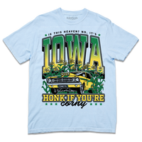 A Comfort Colors hydrangea t-shirt with green & gold ink that says, "Is this heaven? No, It's Iowa. Honk if you're corny" with a graphic of an old muscle car driving out of corn fields with a cat behind the steering wheel.