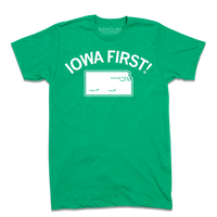 Short sleeve heather kelly green t-shirt with white ink print. Curved text near the top says, "IOWA FIRST!" above a map of Kansas with cities in KS marked on it like a map.