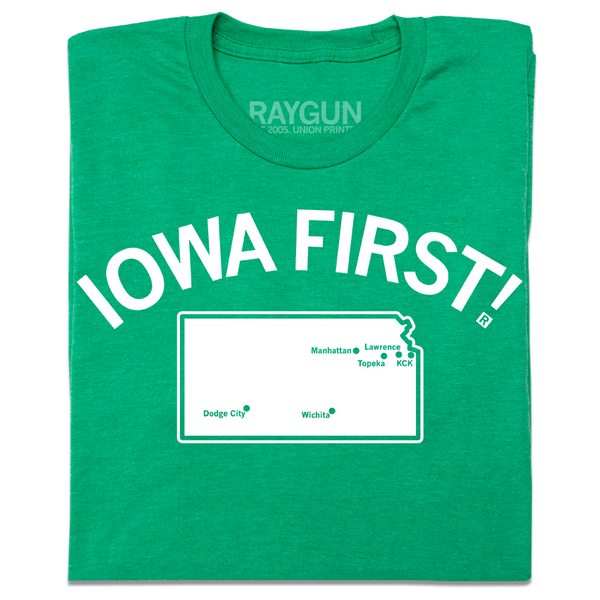 A folded heather kelly green t-shirt with white ink print. Curved text near the top says, 