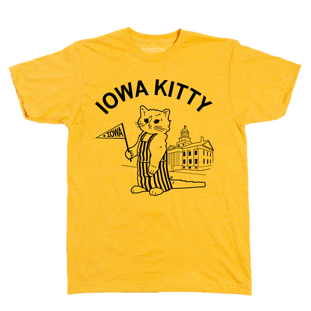 A heather yellow t-shirt that says "Iowa Kitty" in black curved font over an image of RAYGUN's cat mascot, Gary, wearing striped overalls and holding a small Iowa flag in front of the old capitol building in Iowa City.