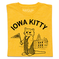 A folded heather gold shirt that says "Iowa Kitty" in black curved font over an image of RAYGUN's cat mascot, Gary, wearing striped overalls and holding a small Iowa flag in front of the old capitol building in Iowa City.