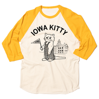 An off-white baseball tee with gold 3/4 sleeves that says "Iowa Kitty" in black curved font over an image of RAYGUN's cat mascot, Gary, wearing striped overalls and holding a small Iowa flag in front of the old capitol building in Iowa City.