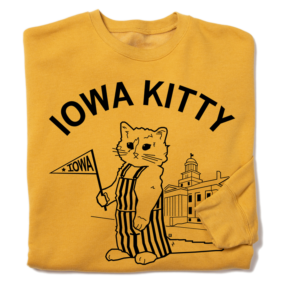 A folded mustard yellow crewneck sweatshirt that says "Iowa Kitty" in black curved font over an image of RAYGUN's cat mascot, Gary, wearing striped overalls and holding a small Iowa flag in front of the old capitol building in Iowa City.