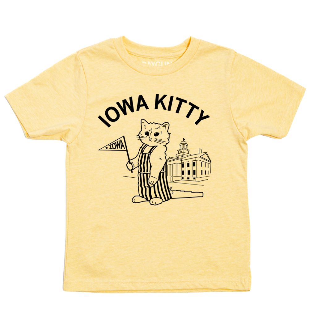 A pastel yellow kids size t-shirt that says "Iowa Kitty" in black curved font over an image of RAYGUN's cat mascot, Gary, wearing striped overalls and holding a small Iowa flag in front of the old capitol building in Iowa City.