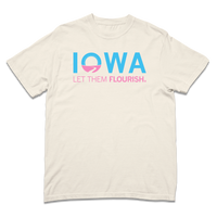 A folded heavyweight cream t-shirt with bright blue and pink print spoofing the Welcome to Iowa road signs by saying "Iowa Let Them Flourish."