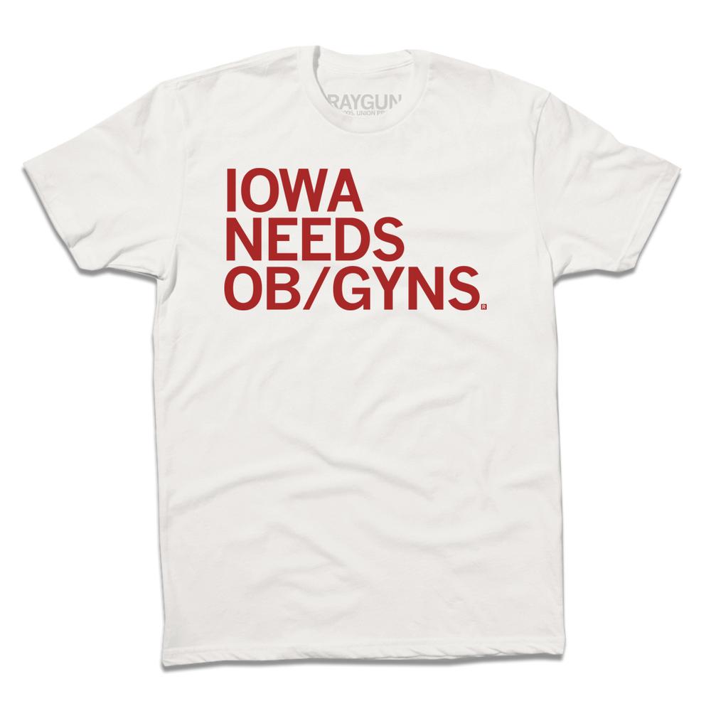 A dull white t-shirt with red left-aligned ink that reads "Iowa Needs OB/GYNs"