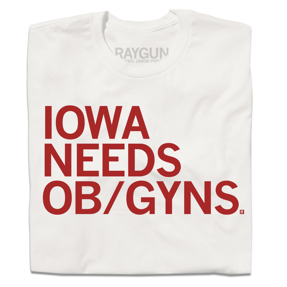 A folded off-white shirt with red left-aligned ink that reads "Iowa Needs OB/GYNs"