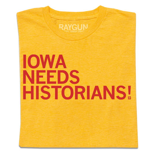 Folded gold shirt with bright red text that reads "Iowa Needs Historians!"