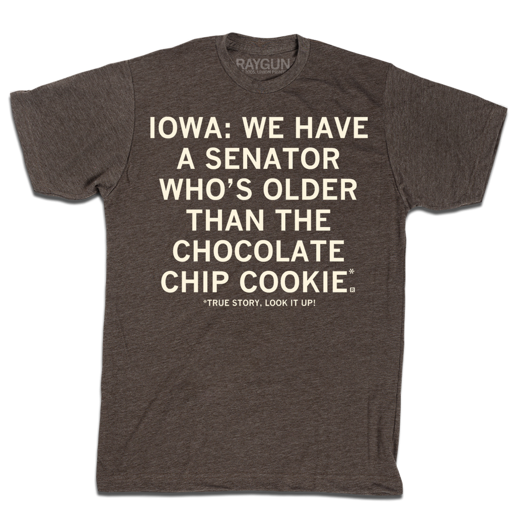 A heather brown tee with off white ink that says, "Iowa: We have a senator who's older than the chocolate chip cookie. True story, look it up!"