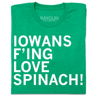 A folded heather kelly green t-shirt with left-aligned white ink text that reads "Iowans f'ing love spinach!"