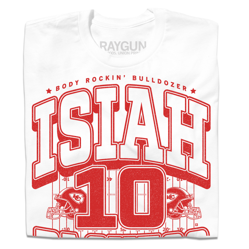 A folded white t-shirt with red ink that reads "The Body Rockin' Bulldozer, Isiah Pachecho #10. The ground hates to see him running" over an illustration of a football field with a football helmet to either side.