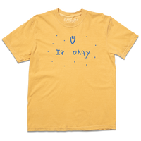 Comfort Colors heavyweight mustard t-shirt with blue print that says, "It Okay" with a smiley face above and dots scattered around. This shirt was designed by a kid taking part in a contest at our Cedar Rapids store.