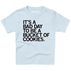 A light blue youth sized t-shirt with left aligned black text in all caps that says, "It's a bad day to be a bucket of cookies."