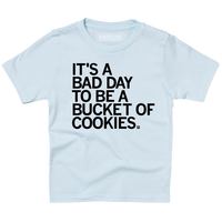 A light blue youth sized t-shirt with left aligned black text in all caps that says, "It's a bad day to be a bucket of cookies."