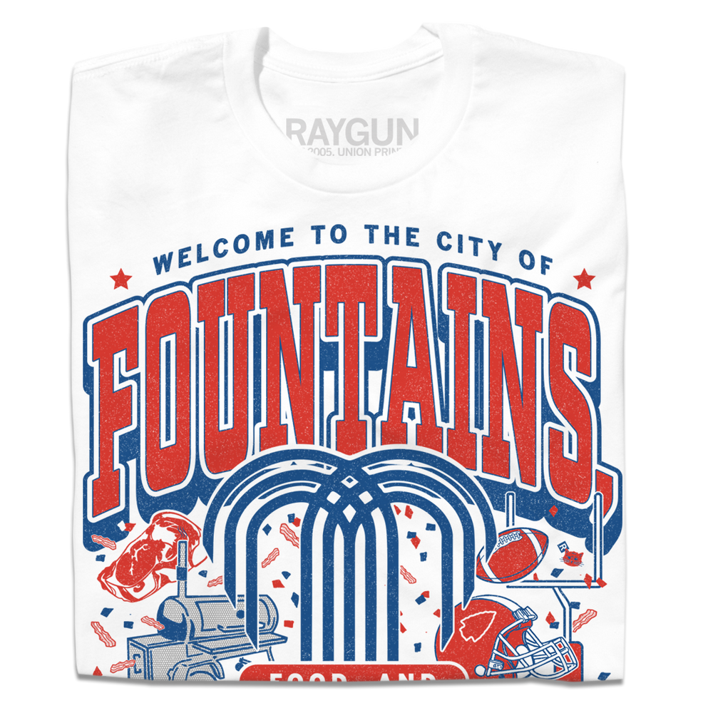 White shirt with red & blue ink that says, "Welcome to the city of fountains, food, and football. Kansas City, Missouri USA" with a fountain, football, helmet, goalpost, smoker, and steak in the background.