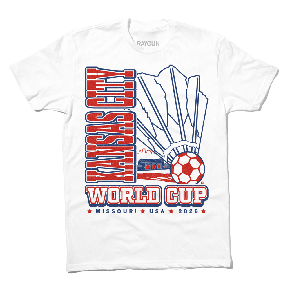 White shirt with red & royal blue ink depicting a giant shuttlecock with a soccer ball at the end in front of an outline of the KC skyline. Text reads "World Cup Kansas City, Missouri. USA 2026."