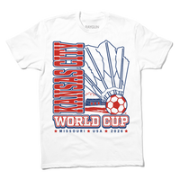 White shirt with red & royal blue ink depicting a giant shuttlecock with a soccer ball at the end in front of an outline of the KC skyline. Text reads "World Cup Kansas City, Missouri. USA 2026."