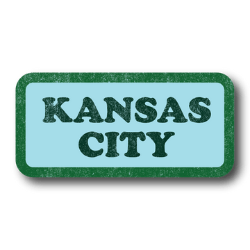 Pastel blue rectangular sticker with green border and dark green text in a vintage, faded style that says, "KANSAS CITY"