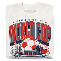 A folded white t-shirt with red & navy ink depicting notable buildings around Kansas City behind a soccer stadium and in front of a giant soccer ball. Text reads "Can I kick it? World Cup Kansas City, Missouri. USA 2026."