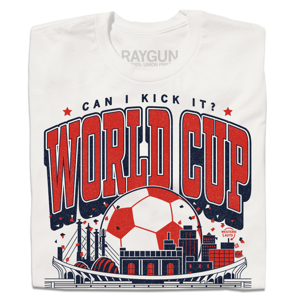 A folded white t-shirt with red & navy ink depicting notable buildings around Kansas City behind a soccer stadium and in front of a giant soccer ball. Text reads 