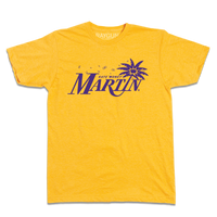 Heather gold t-shirt with purple ink that reads "Kate "Money" Martin" with the I being a leaning palm tree that has the state of Iowa in the center of its leaves. There are also flying dollar bills above the text.