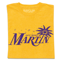 A folded heather yellow t-shirt with purple ink that reads "Kate "Money" Martin" with the I being a leaning palm tree that has the state of Iowa in the center of its leaves.