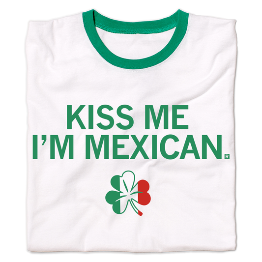 White ringer t-shirt featuring the text KISS ME IM MEXICAN in green letters above a shamrock graphic colored with the green, white, and red stripes of the Mexican flag.