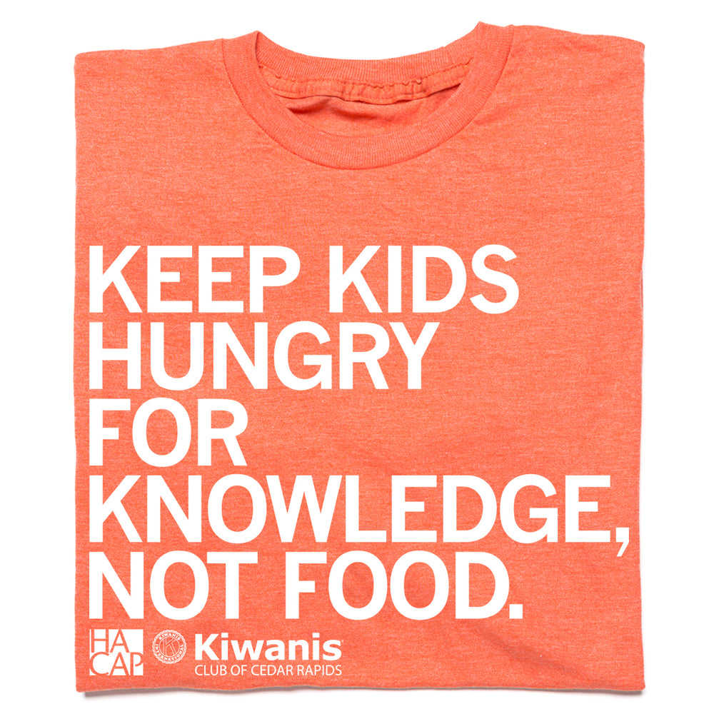A folded heather orange t-shirt with left aligned white print that reads "Keep kids hungry for knowledge, not food" with the HACAP and Kiwanis Club of Cedar Rapids logos in the bottom left.