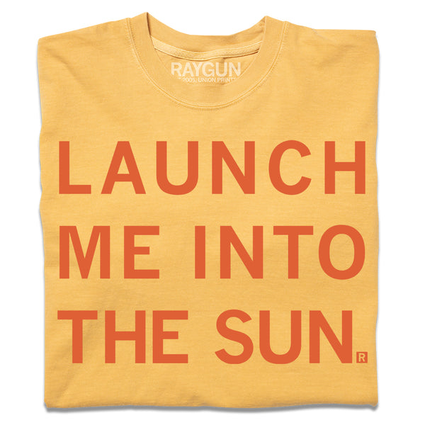 A folded gold heavyweight t-shirt with centered orange ink text that says, 