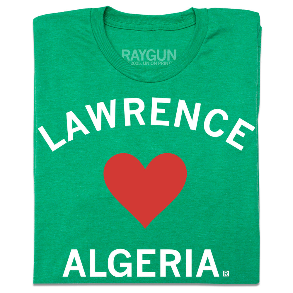 A folded heather green t-shirt with a red  heart in the center and white text that says, "Lawrence" above the heart and "Algeria" below it.