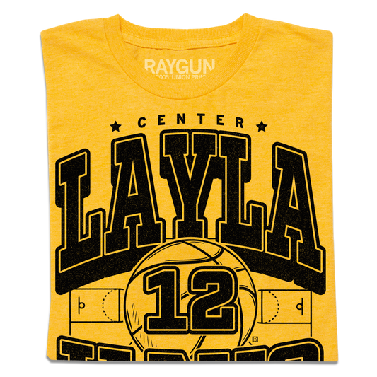 Heather mellow yellow t-shirt featuring the name LAYLA in large black varsity-style letters above a basketball graphic with the number 12.