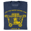 Heather denim navy blue t-shirt featuring a yellow graphic of a lion in a circus wagon with the text Leo the paper eating lion and Lincoln, NE.