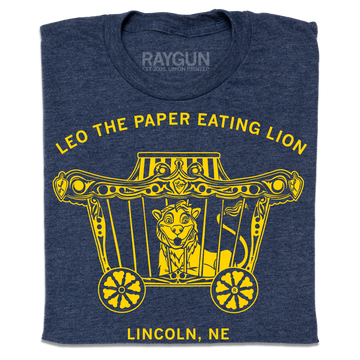 Heather denim navy blue t-shirt featuring a yellow graphic of a lion in a circus wagon with the text Leo the paper eating lion and Lincoln, NE.