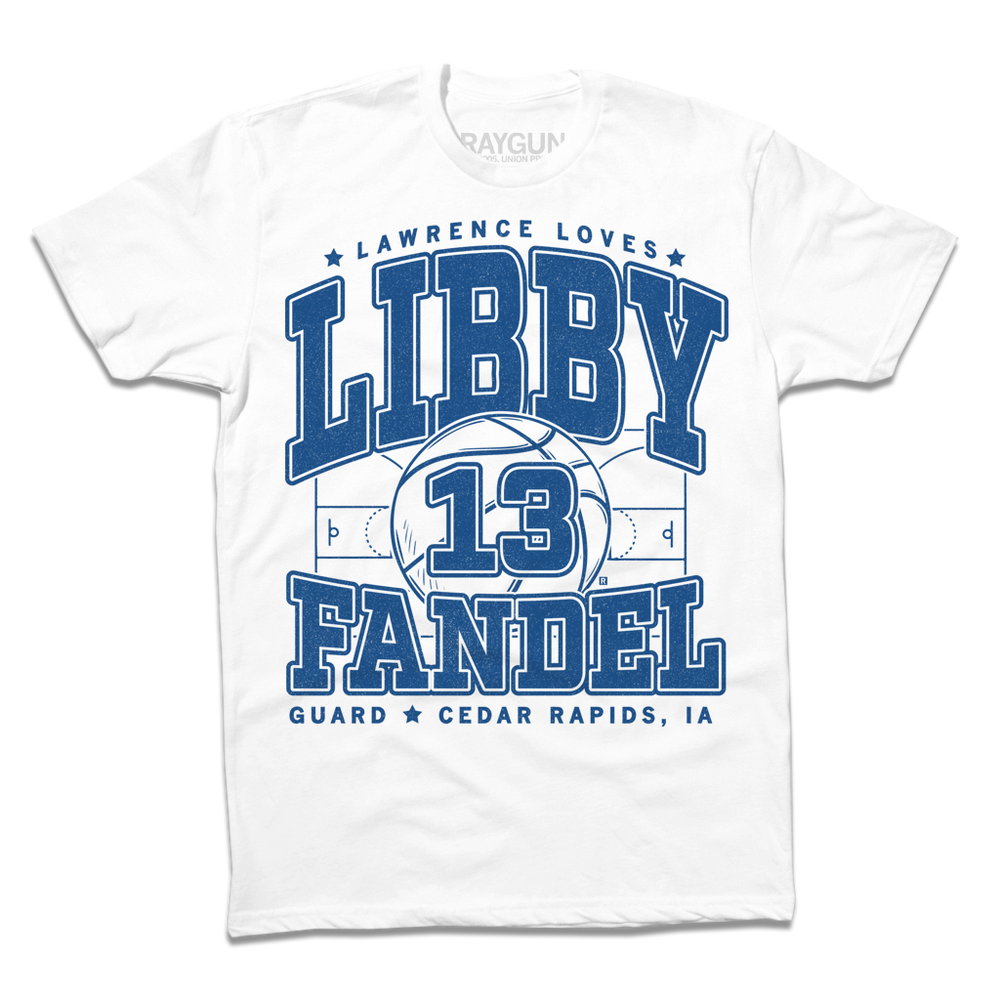 A white shirt with royal blue ink that says, "Lawrence loves" in small font above large text "Libby Fandel" with an illustration of a basketball court in the center and a giant basketball in the center with the number 13. In smaller font at the bottom reads "Guard. Cedar Rapids, IA"