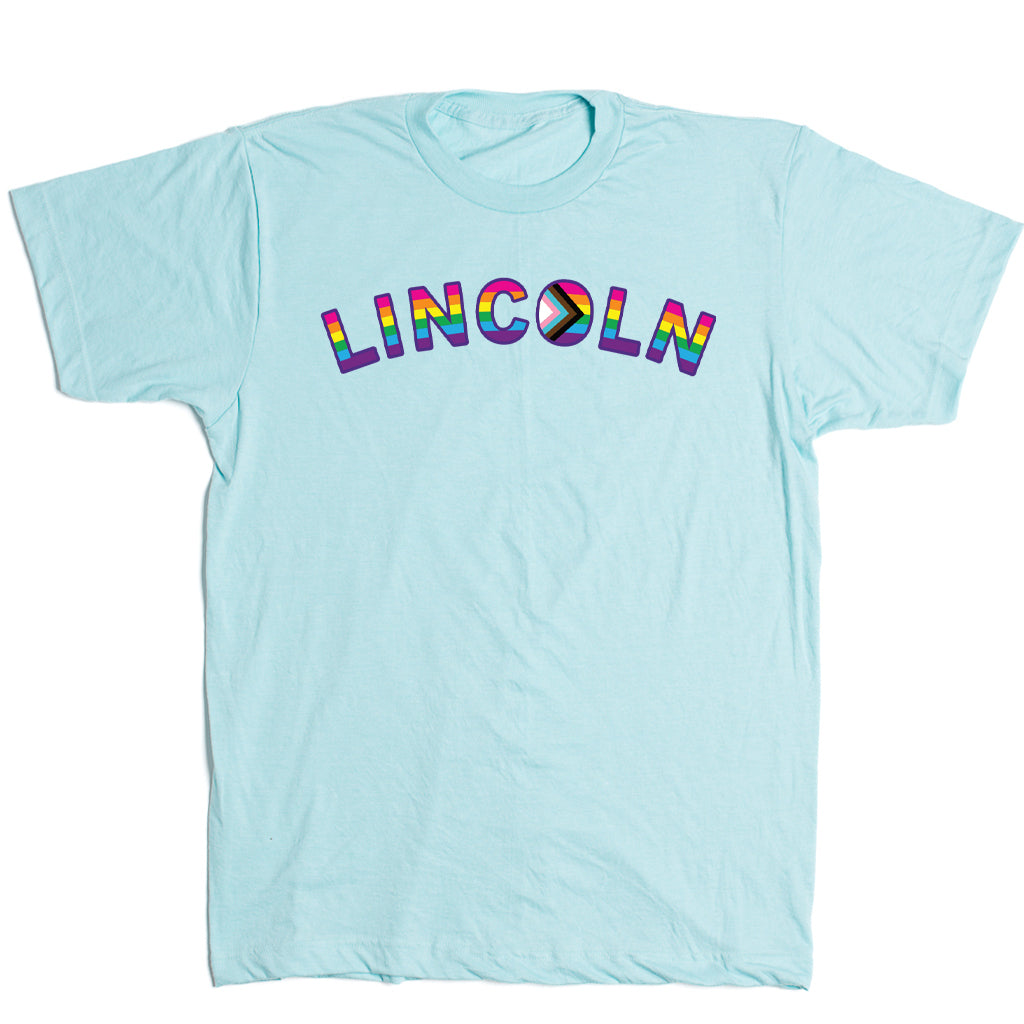 Light blue RAYGUN t-shirt with the word LINCOLN printed across the chest in a rainbow-colored font for Lincoln NE Pride.