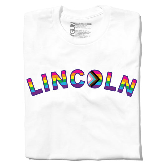 White RAYGUN t-shirt with LINCOLN printed in rainbow-striped, block-style lettering across the chest, celebrating Lincoln NE Pride.