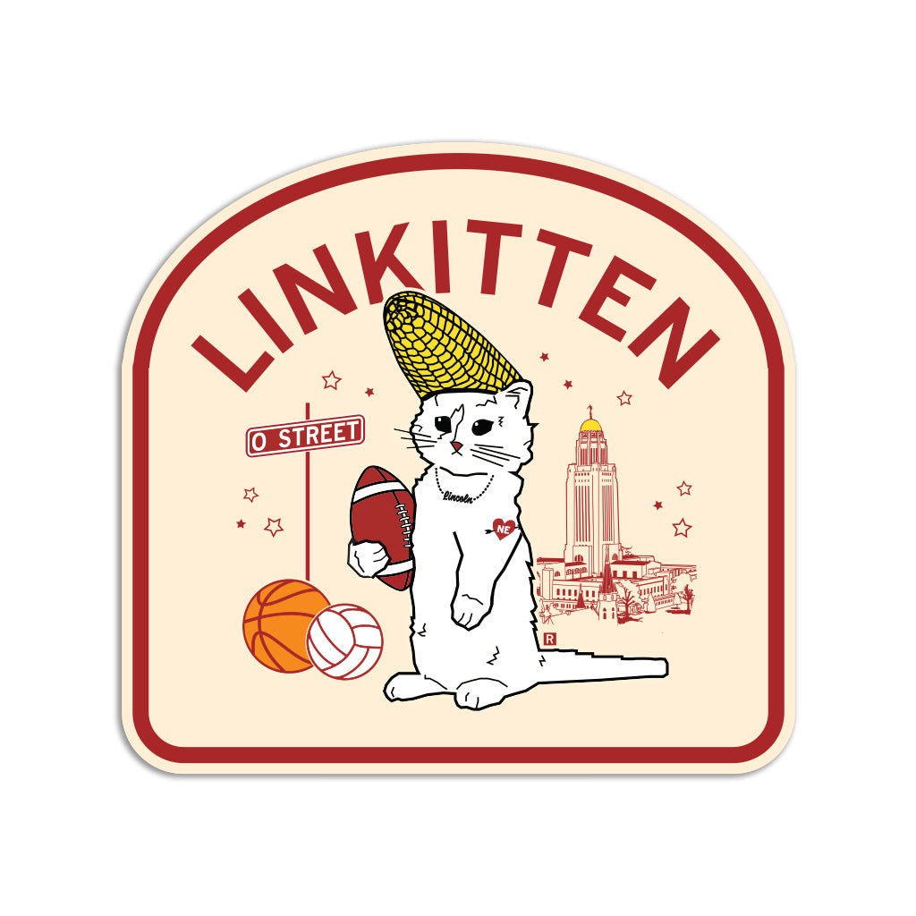 A RAYGUN vinyl sticker featuring a cat wearing a corn cob hat, holding a football beside a basketball and volleyball. The design includes LINKITTEN text, a street sign, and the Nebraska State Capitol in the background.