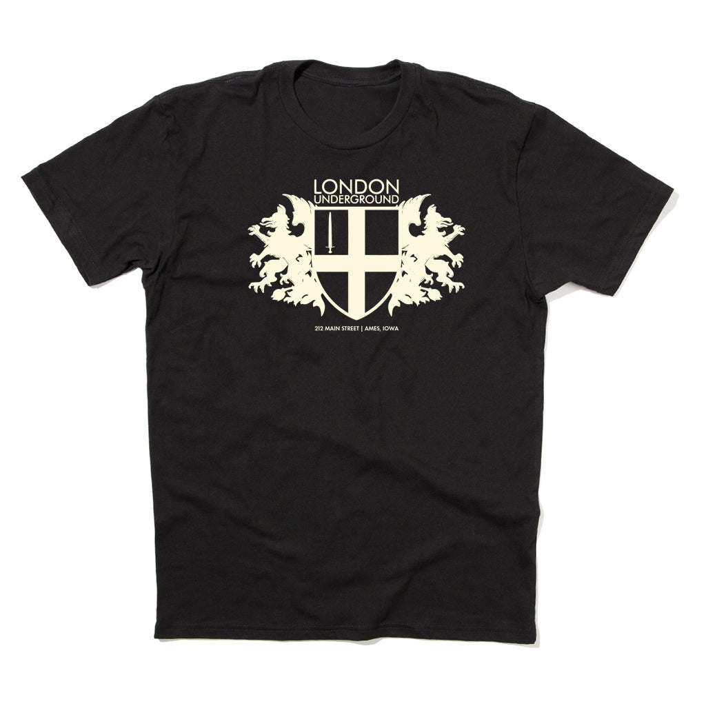 Black RAYGUN t-shirt with a white London Underground graphic of a shield, a sword, and two lions, featuring the text 212 Main Street | Ames, Iowa.