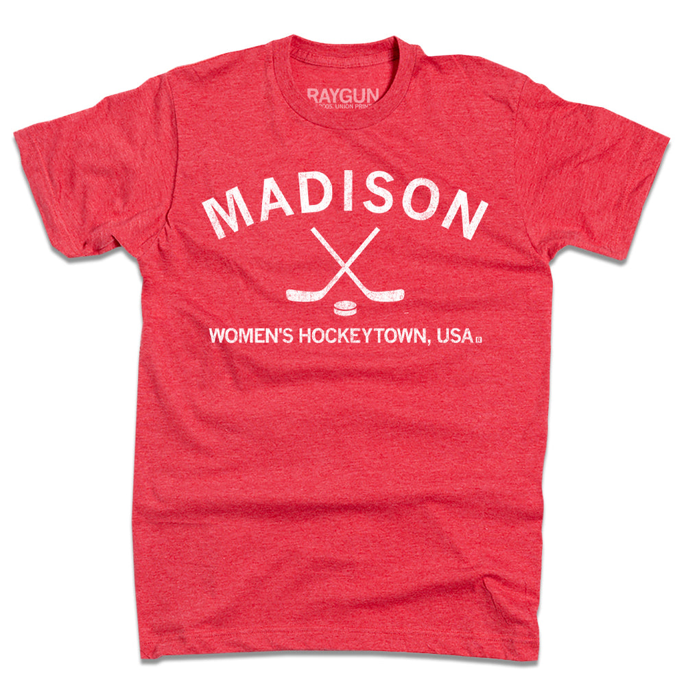Heather red shirt with white ink that reads "Madison. Women's Hockeytown, USA." with crossing hockey sticks and a puck in the center.