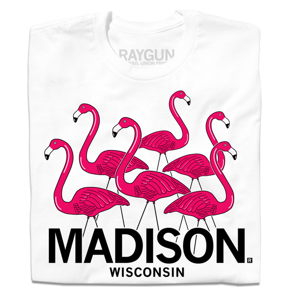 A folded white t-shirt with an illustration of six lawn flamingos looking in different directions above 