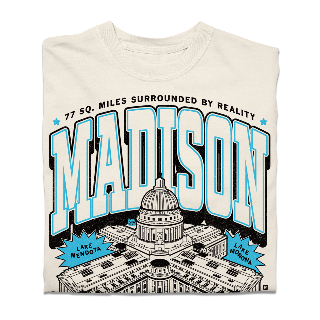 Cream-colored heavyweight Madison, WI t-shirt featuring a graphic of the State Capitol, the text MADISON, 77 SQ. MILES SURROUNDED BY REALITY, and labels for Lake Mendota and Lake Monona.