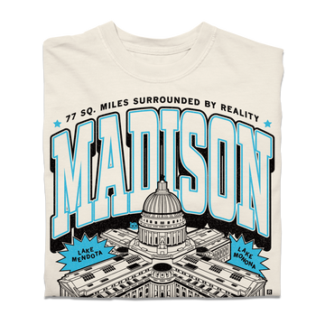 Cream-colored heavyweight Madison, WI t-shirt featuring a graphic of the State Capitol, the text MADISON, 77 SQ. MILES SURROUNDED BY REALITY, and labels for Lake Mendota and Lake Monona.